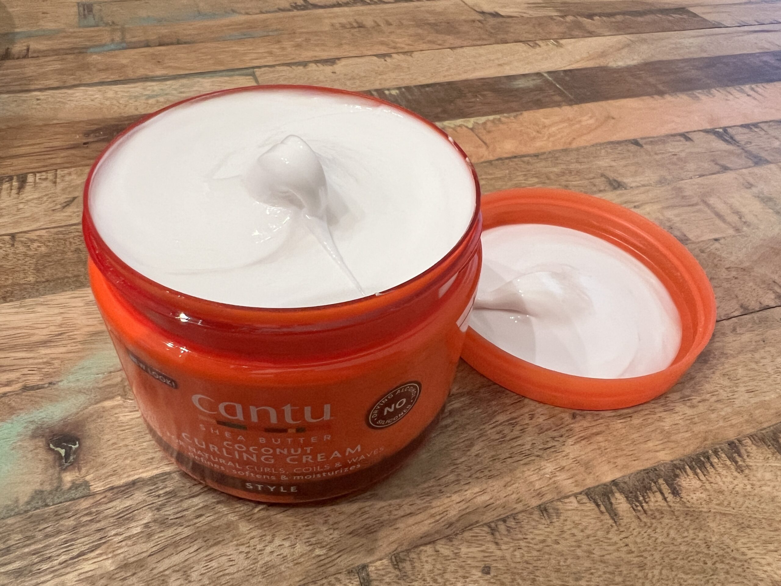 Close-up view of the creamy texture of Cantu Coconut Curling Cream, emphasizing its richness for hair care.
