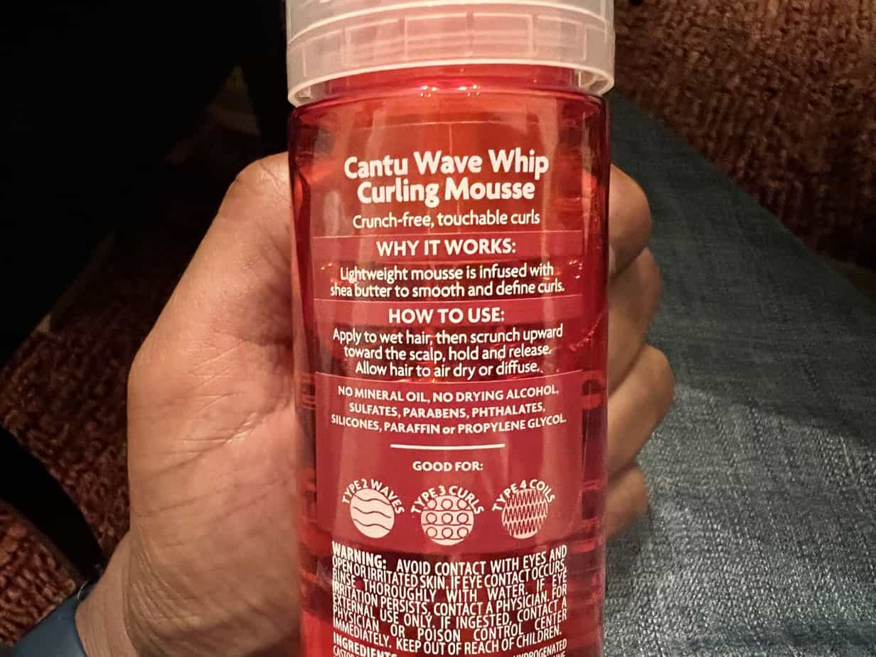 Application of Cantu Shea Butter Wave Whip Curling Mousse, showcasing its lightweight formula for curl definition.