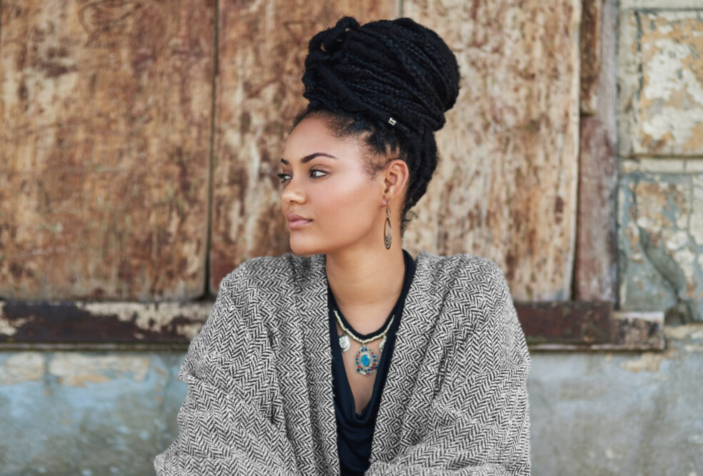 Side view of box braids wrapped into a high bun, with a silver cuff on one braid