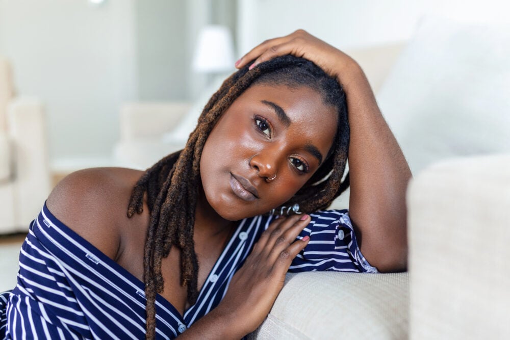 Woman pushing her locs back from her forehead to show her hairline and edges