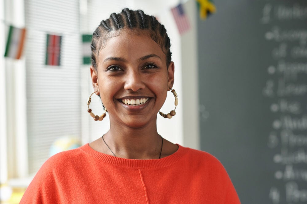 Young Black woman with straight-back cornrows smiling in a classroom