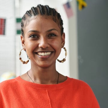 Young Black woman with straight-back cornrows smiling in a classroom