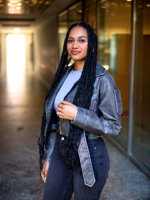 Woman standing in a hallway, her knotless braids reaching her waist with loose, curly ends