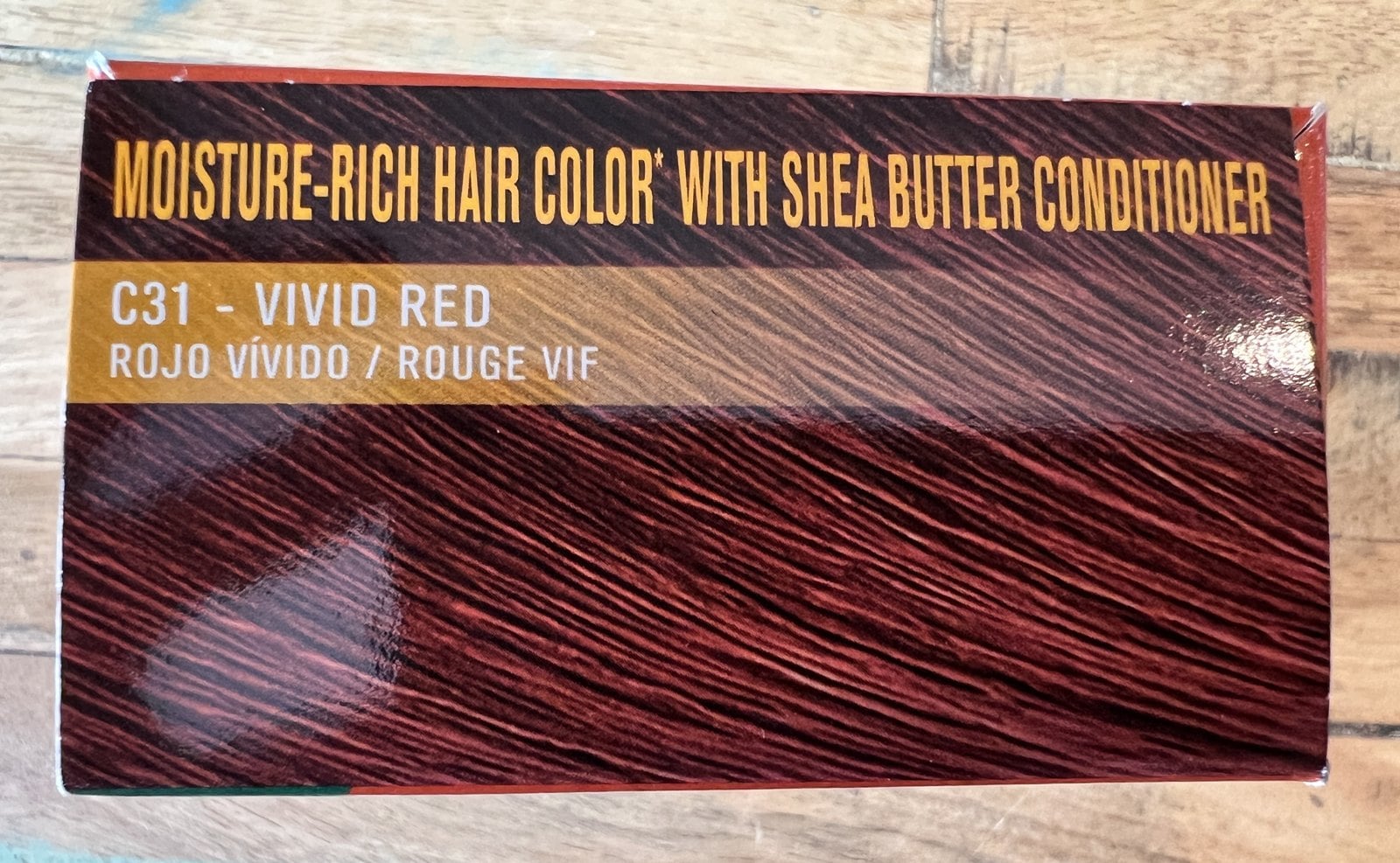 Top of a Creme of Nature hair color box with a dark red swatch and the shade name C31 Vivid Red