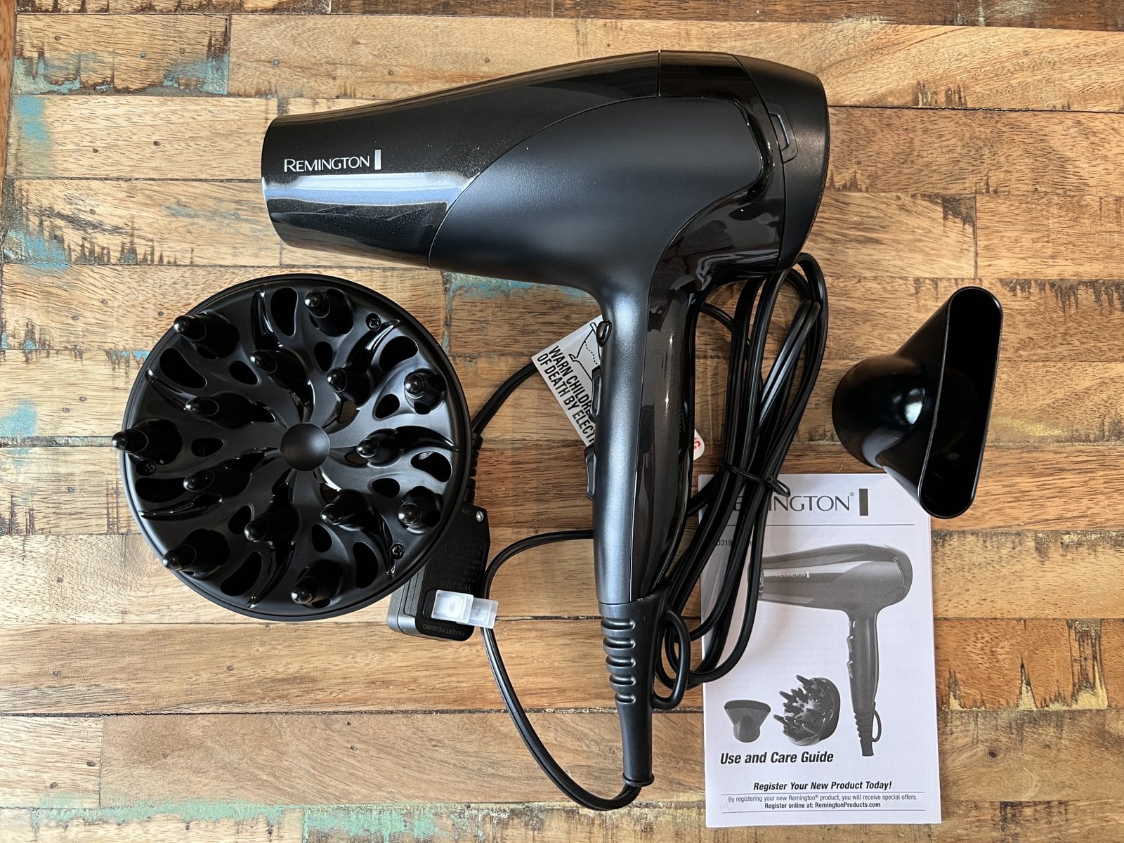 Black Remington hair dryer with a round diffuser on the left and a narrow concentrator nozzle on the right