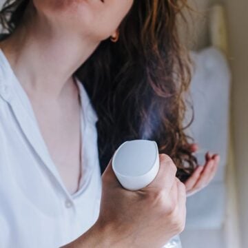 Woman misting her damp wavy hair with a white spray bottle