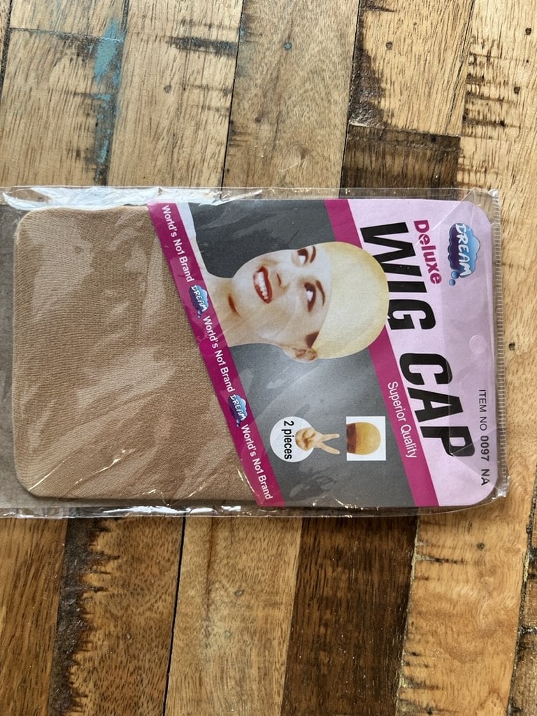 Unopened two-pack of beige stocking wig caps on a wood table